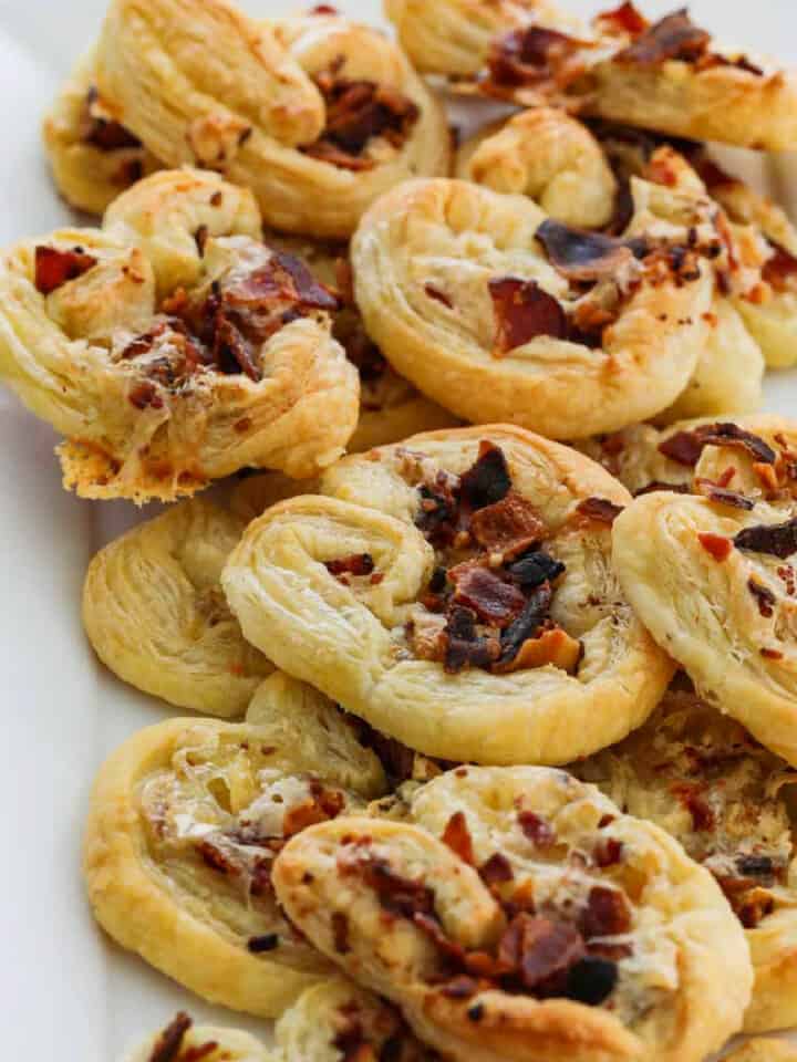 A white platter filled with brie and bacon palmier appetizers golden brown and ready to eat.