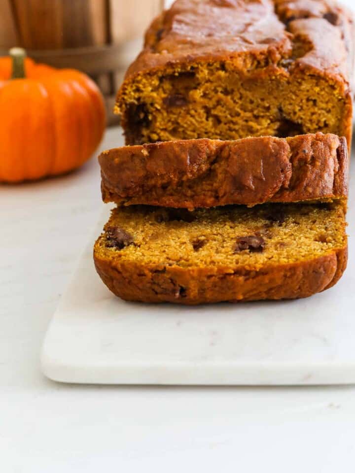 Thick sliced loaf of pumpkin bread on a marble cutting board.