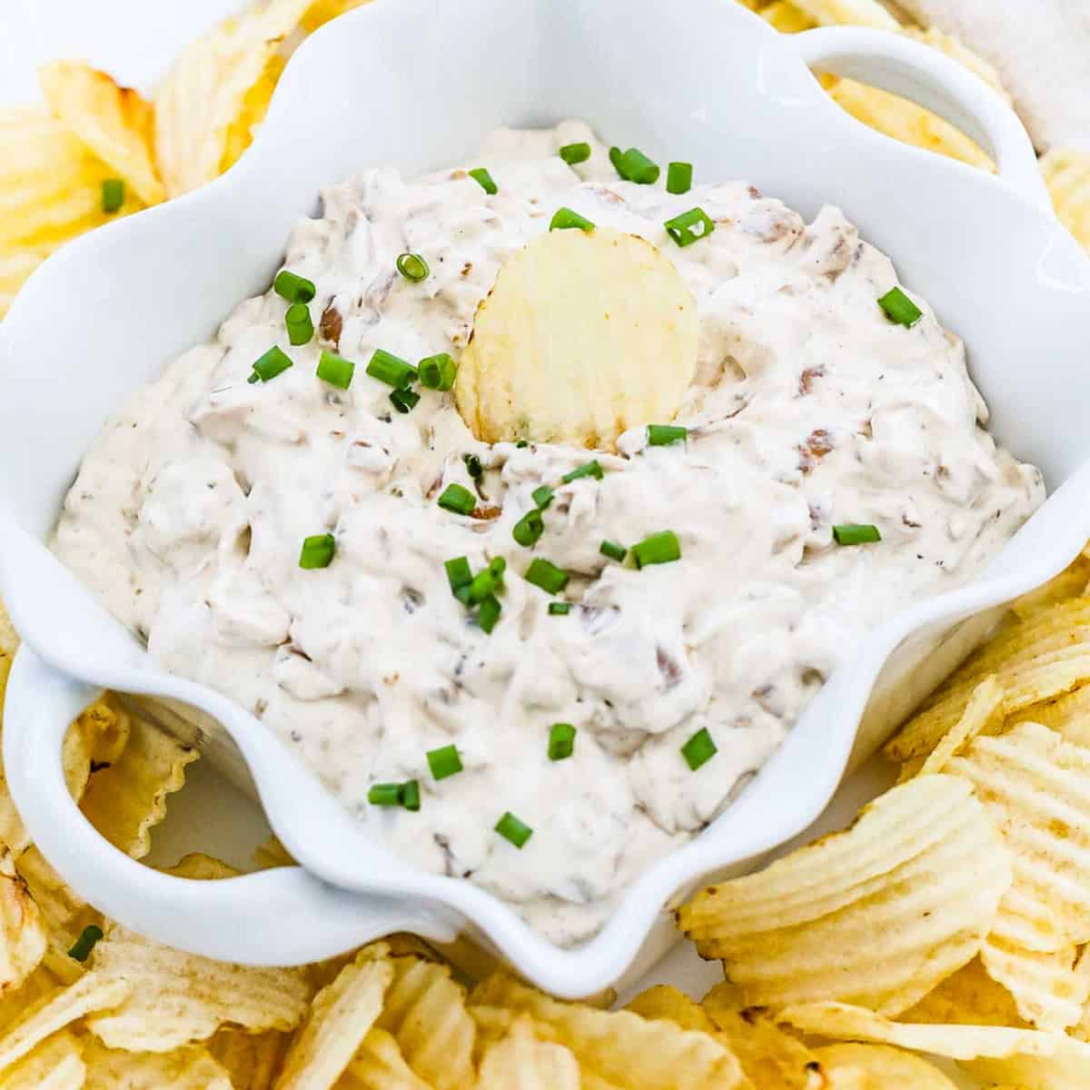 Ruffled potato chips on a plate with homemade French onion dip.