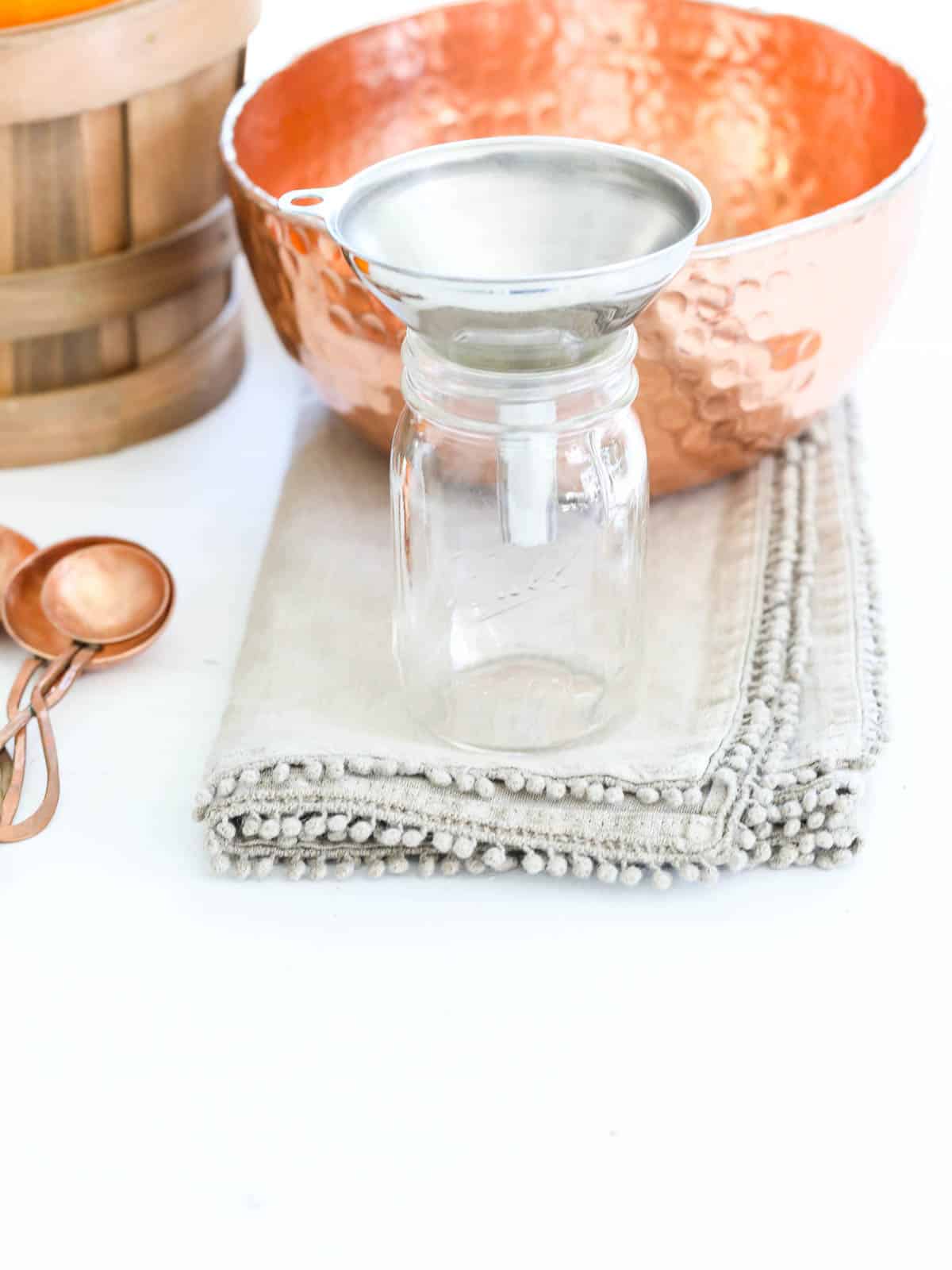 A mini ball jar with funnel to fill with pumpkin pie spice.