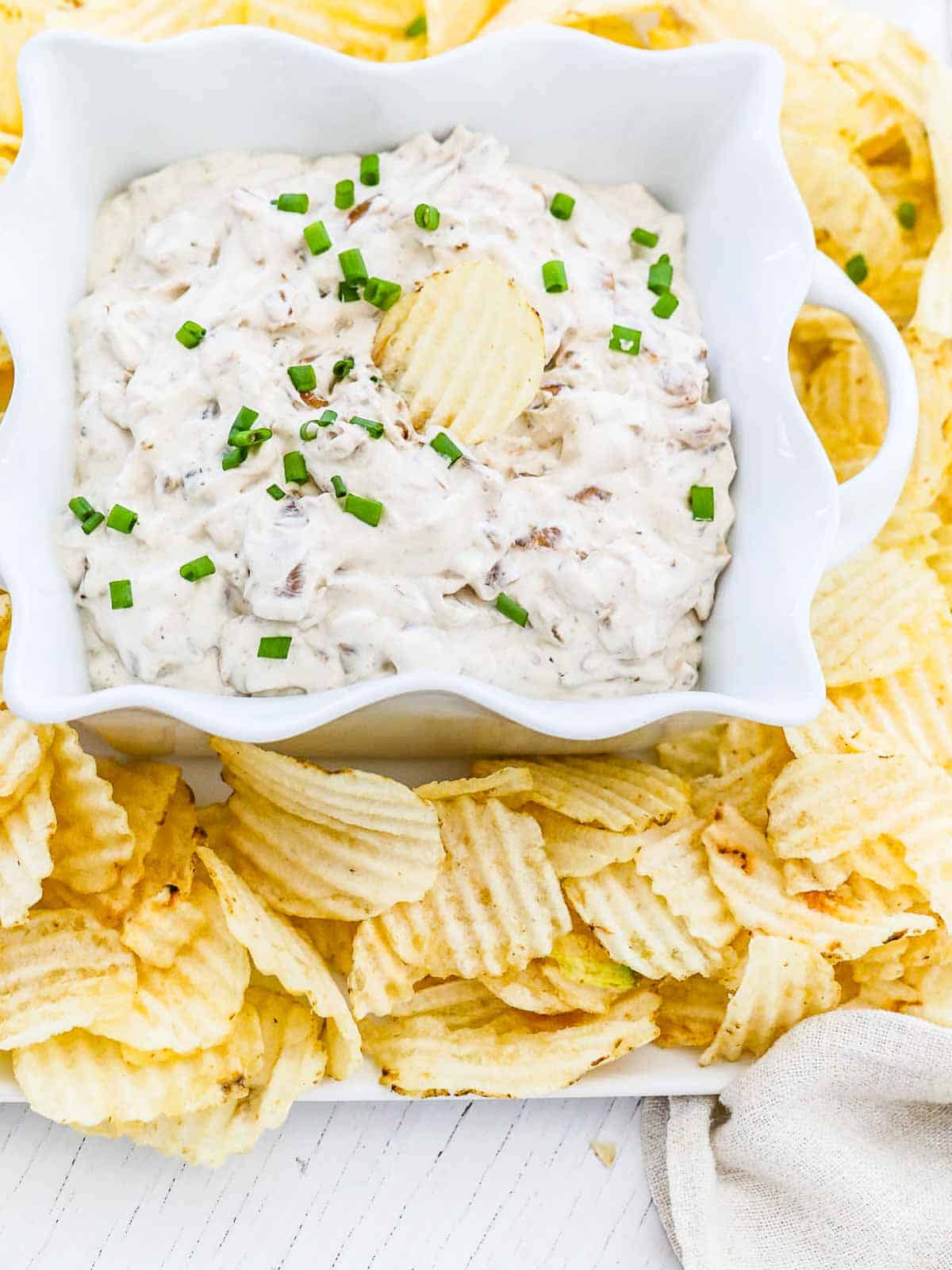 Ruffled potato chips on a plate with homemade French onion dip.