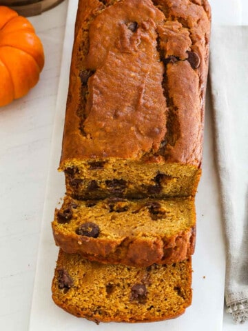 A baked loaf of pumpkin bread sliced thick with a silver knife.s