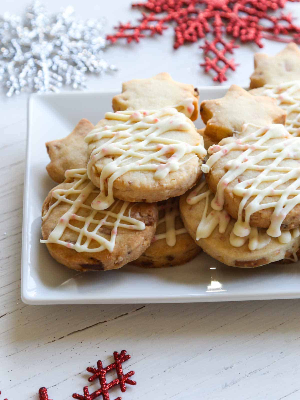 A small white platter with pineapple shaped peppermint shortbread cookies drizzled with icing.