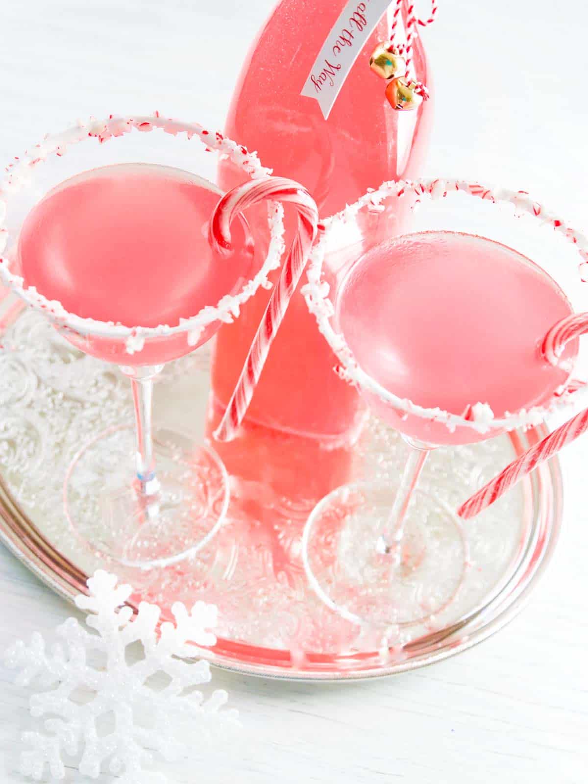 A silver tray with a peppermint martini garnished with a candy cane.