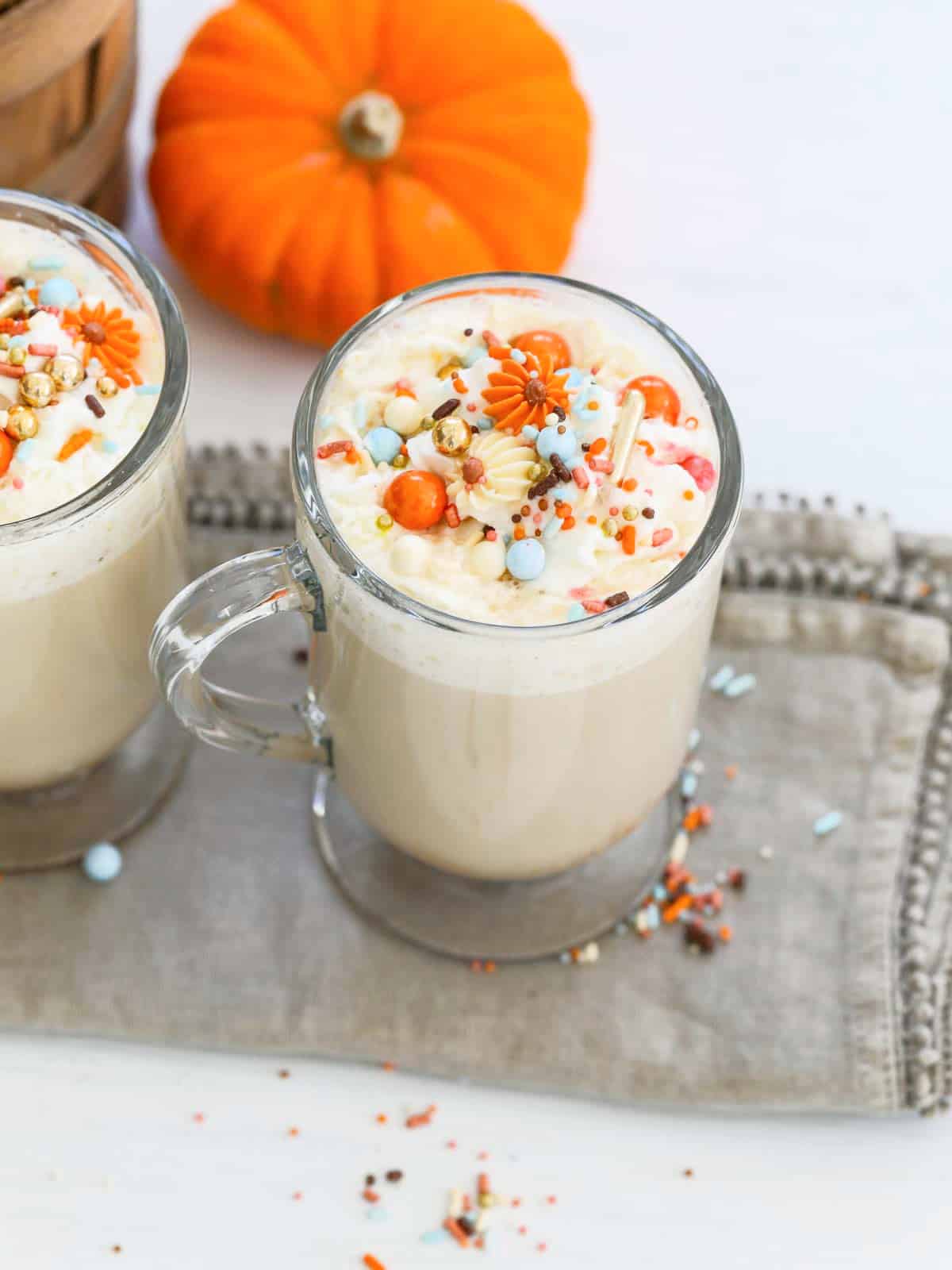 A glass coffee cup filled with Pumpkin Spice Latte topped with sprinkles.