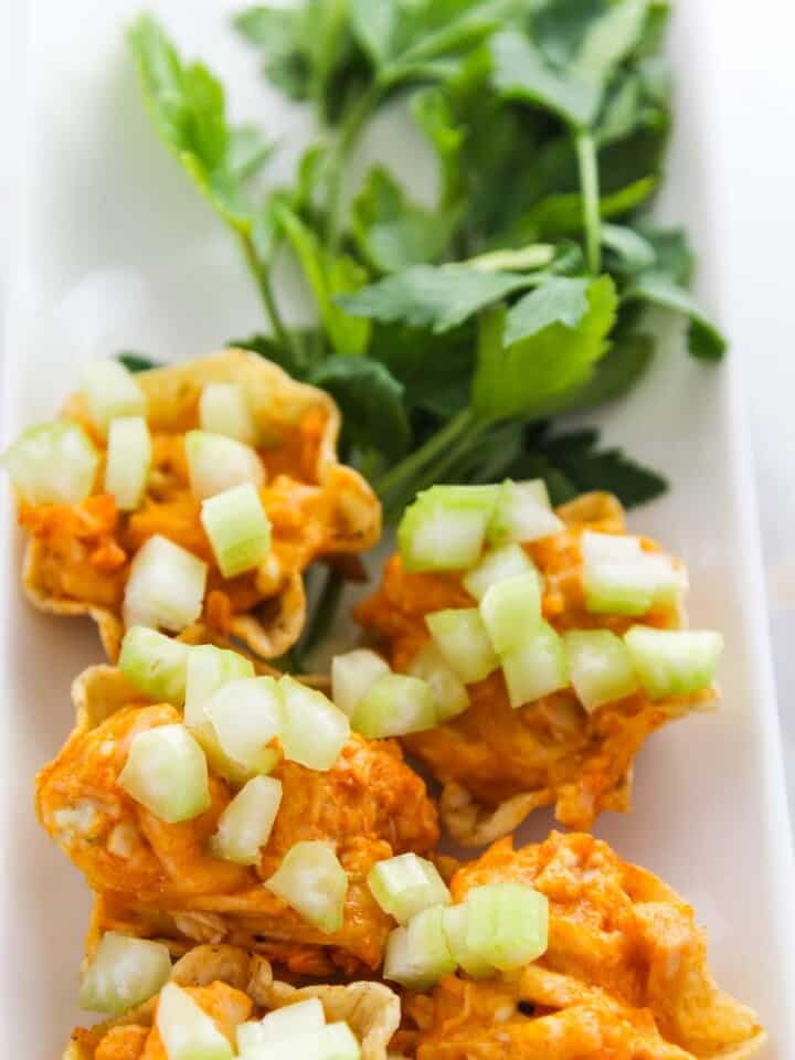 Close up of buffalo chicken baked in tortilla chips garnished with celery.