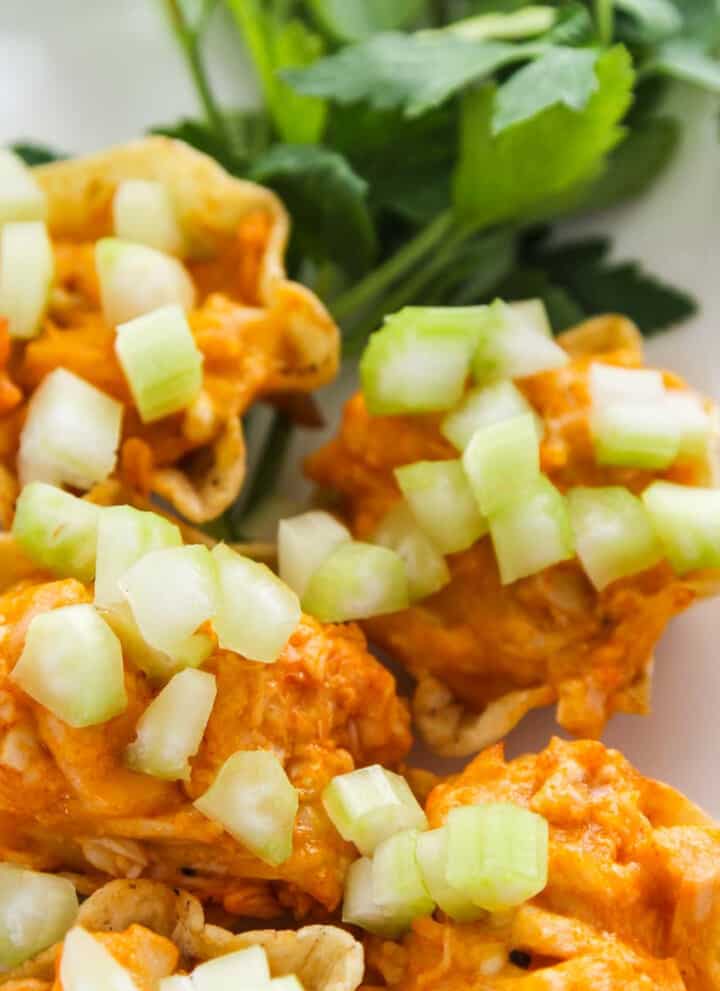 Loaded plate of hot appetizers of Buffalo Chicken on tortilla chips ready for game day food