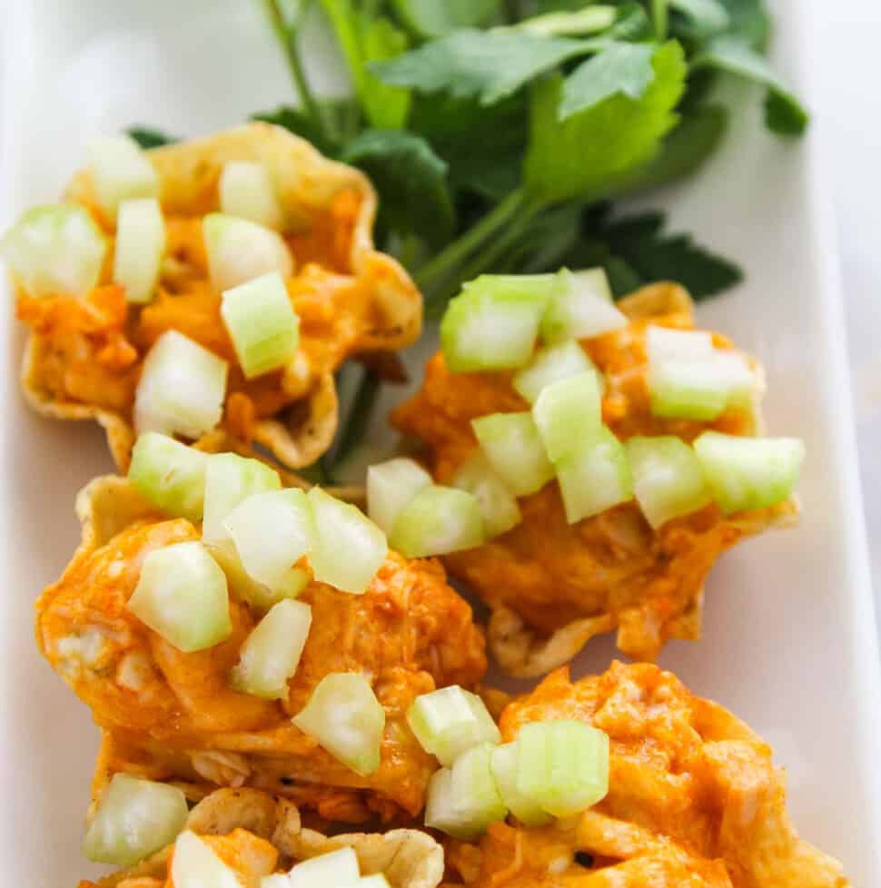 Loaded plate of hot appetizers of Buffalo Chicken on tortilla chips ready for game day food