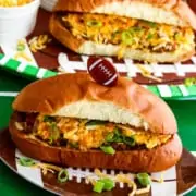 A game day food table with chili dogs loaded with relish, cheese, and onions.
