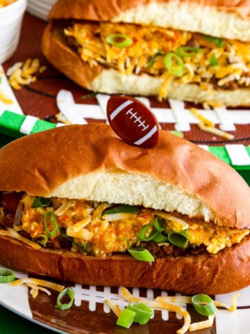 A game day food table with chili dogs loaded with relish, cheese, and onions.