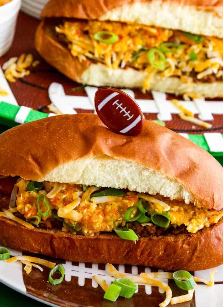 A game day food table with chili dogs loaded with relish, cheese, and onions.