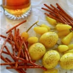 Crinkled parchment paper with a mug of beer, yellow pickled eggs, and pretzel sticks.