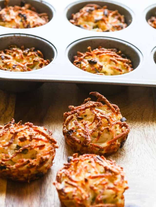 Three golden crispy edged hash browns baked in a muffin tin on cutting board.