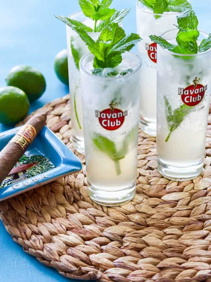 4 mojitos on a woven grass placemat with Cuban cigar nearby.