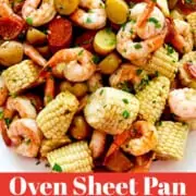 A white platter filled with shrimp boil that has corn, shrimp, sausage, and potatoes.