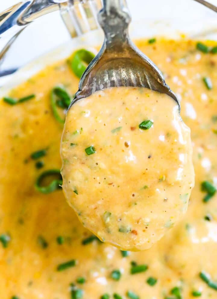 A vintage spoon scooping up remoulade sauce to use on a recipe.