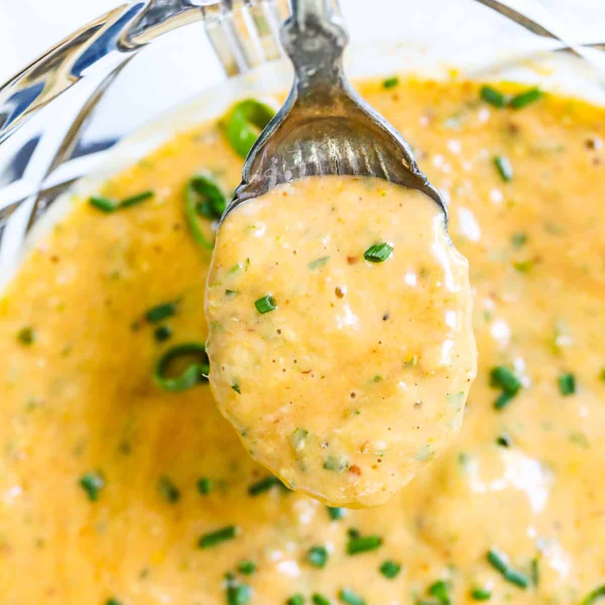 A vintage spoon scooping up remoulade sauce to use on a recipe.