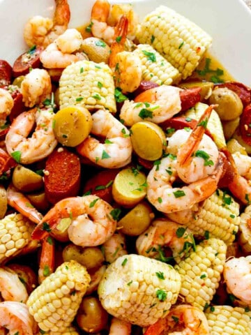 A white platter filled with corn, shrimp, sausage, and potatoes for dinner.