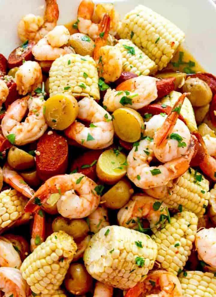 A white platter filled with corn, shrimp, sausage, and potatoes for dinner.