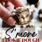 A lady holding a s'more cookie dough truffle cut open with mini marshmallows inside.