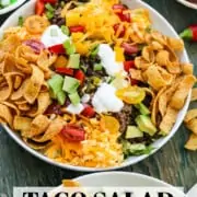 A graphic for Taco Salad showing the white plate filled with the salad and topped with Fritos and grated cheese.
