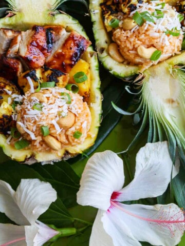 Two pineapple halves carved out filled with coconut rice, grilled pineapple and huli huli chicken.