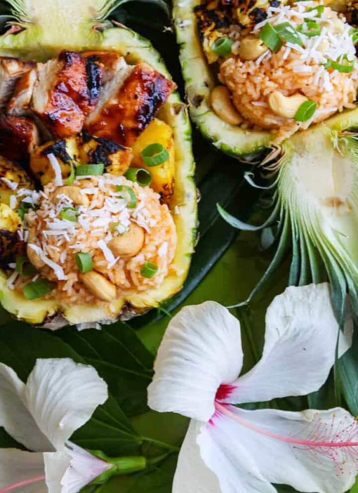 Two pineapple halves carved out filled with coconut rice, grilled pineapple and huli huli chicken.