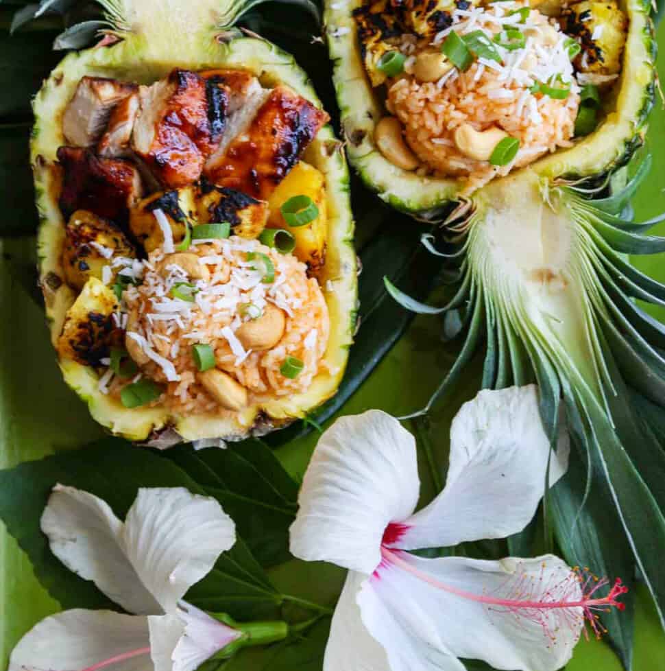 Two pineapple halves carved out filled with coconut rice, grilled pineapple and huli huli chicken.