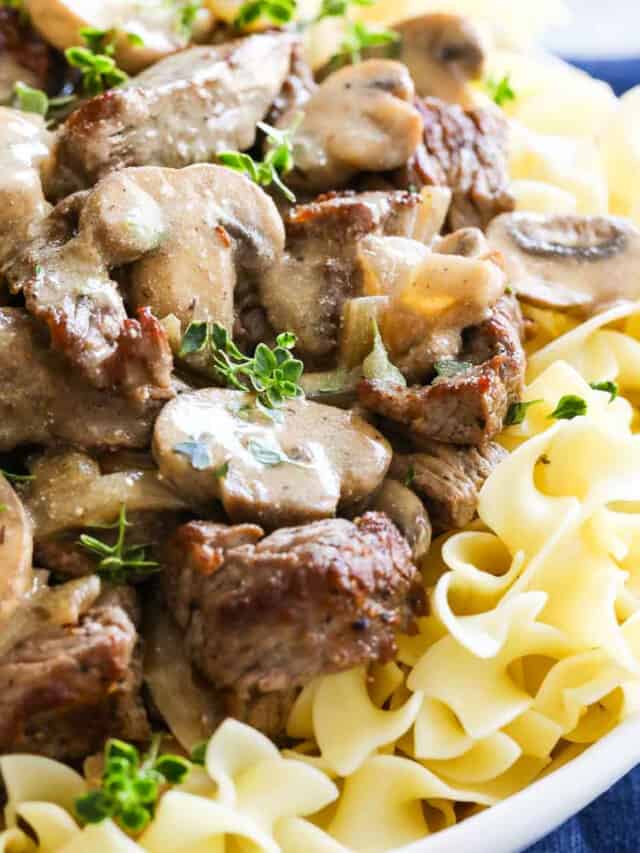 White plate filled with Beef Stroganoff on noodles with mushrooms.