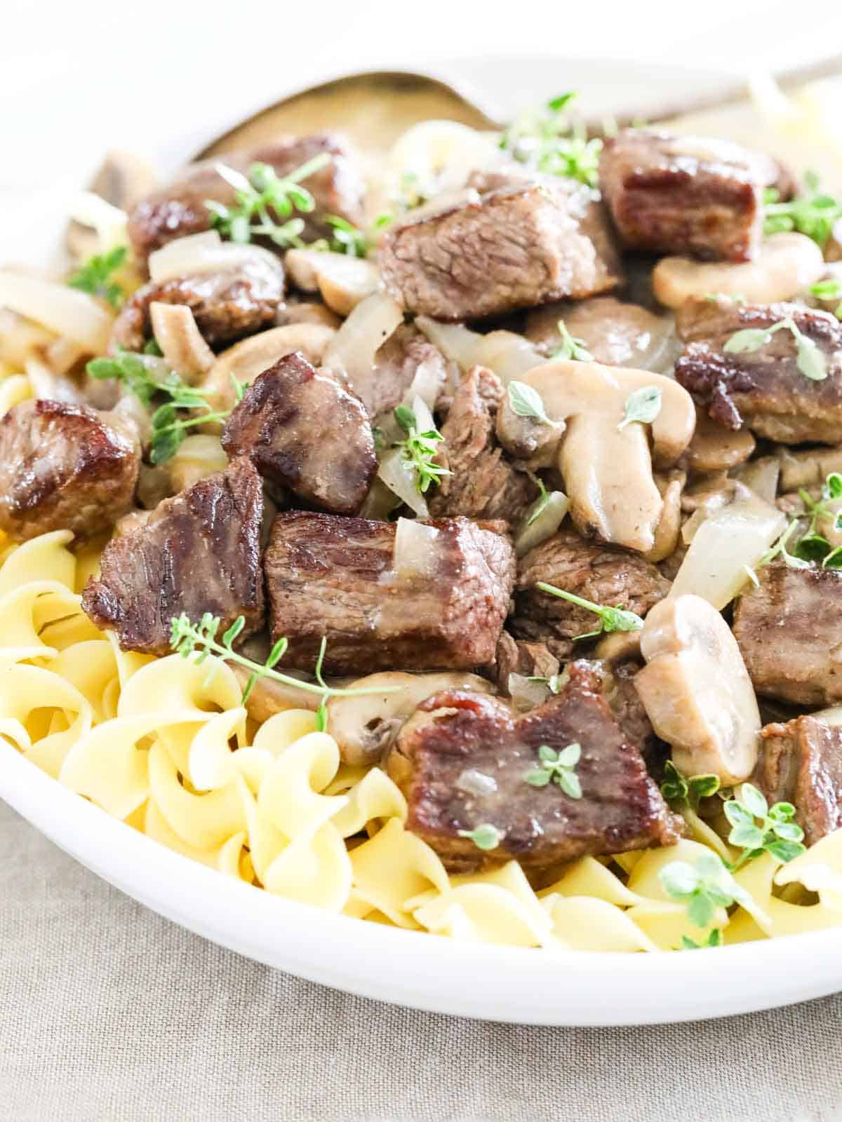 Beef Stroganoff on a white plate with beef and mushrooms.