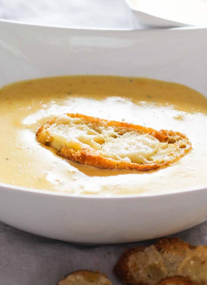 White bowl filled with cheese soup and a homemade crouton on top.