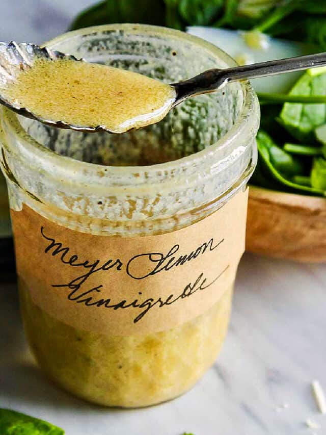 A vintage silver spoon resting on an open jar of vinaigrette.