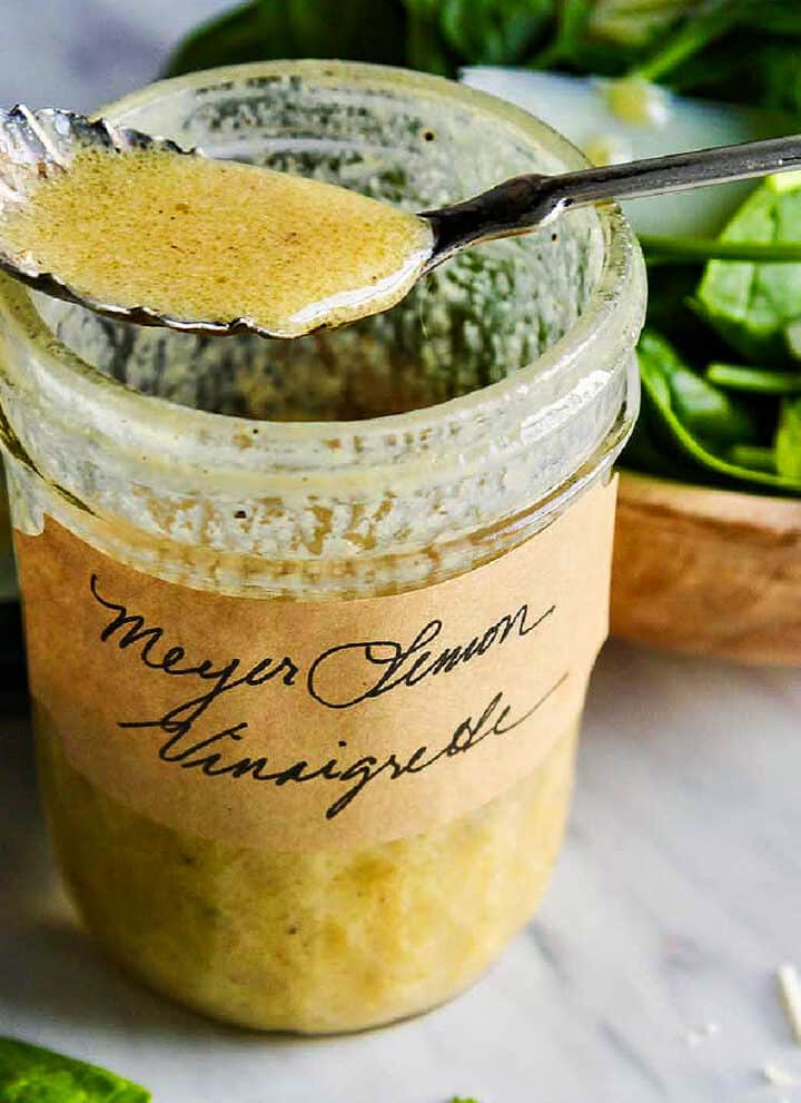 A vintage silver spoon resting on an open jar of vinaigrette.