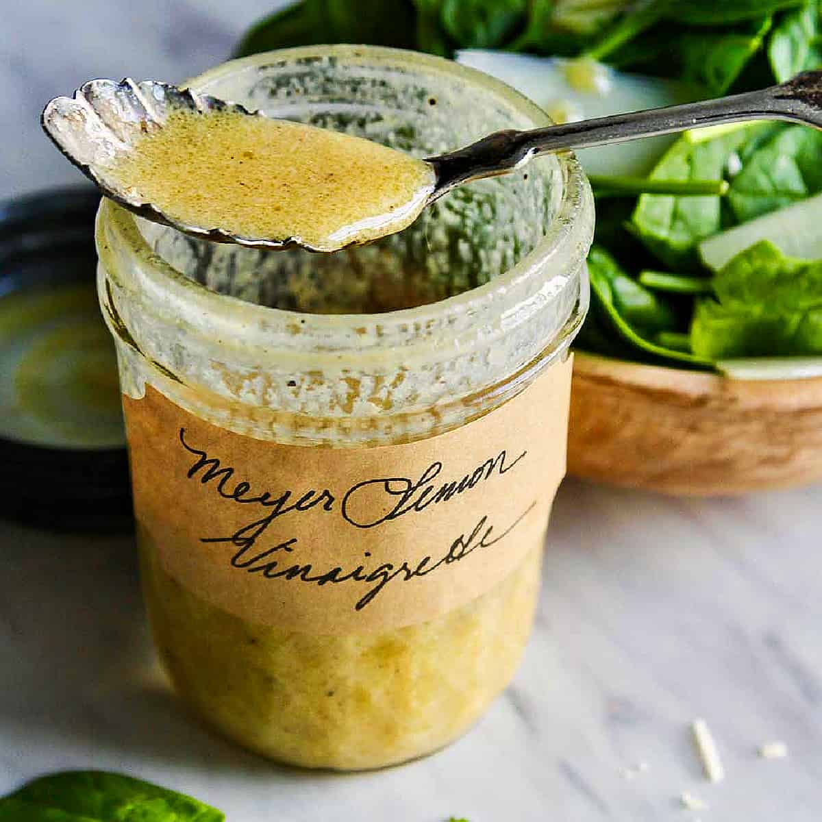 A vintage silver spoon resting on an open jar of vinaigrette.