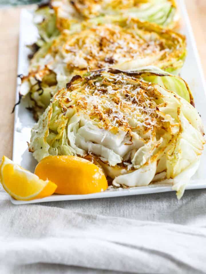 Close up of a roasted cabbage steak on a white platter.