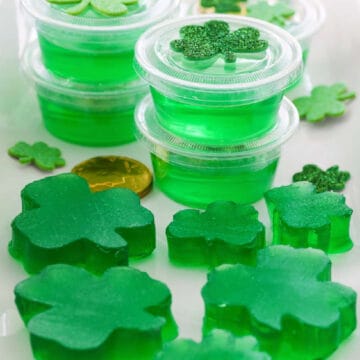 A white rectangle platter with green jello shots and jigglers shaped like shamrocks.