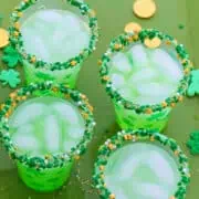Four glasses of green cocktails for St. Patrick's day on a green tray with gold coins.