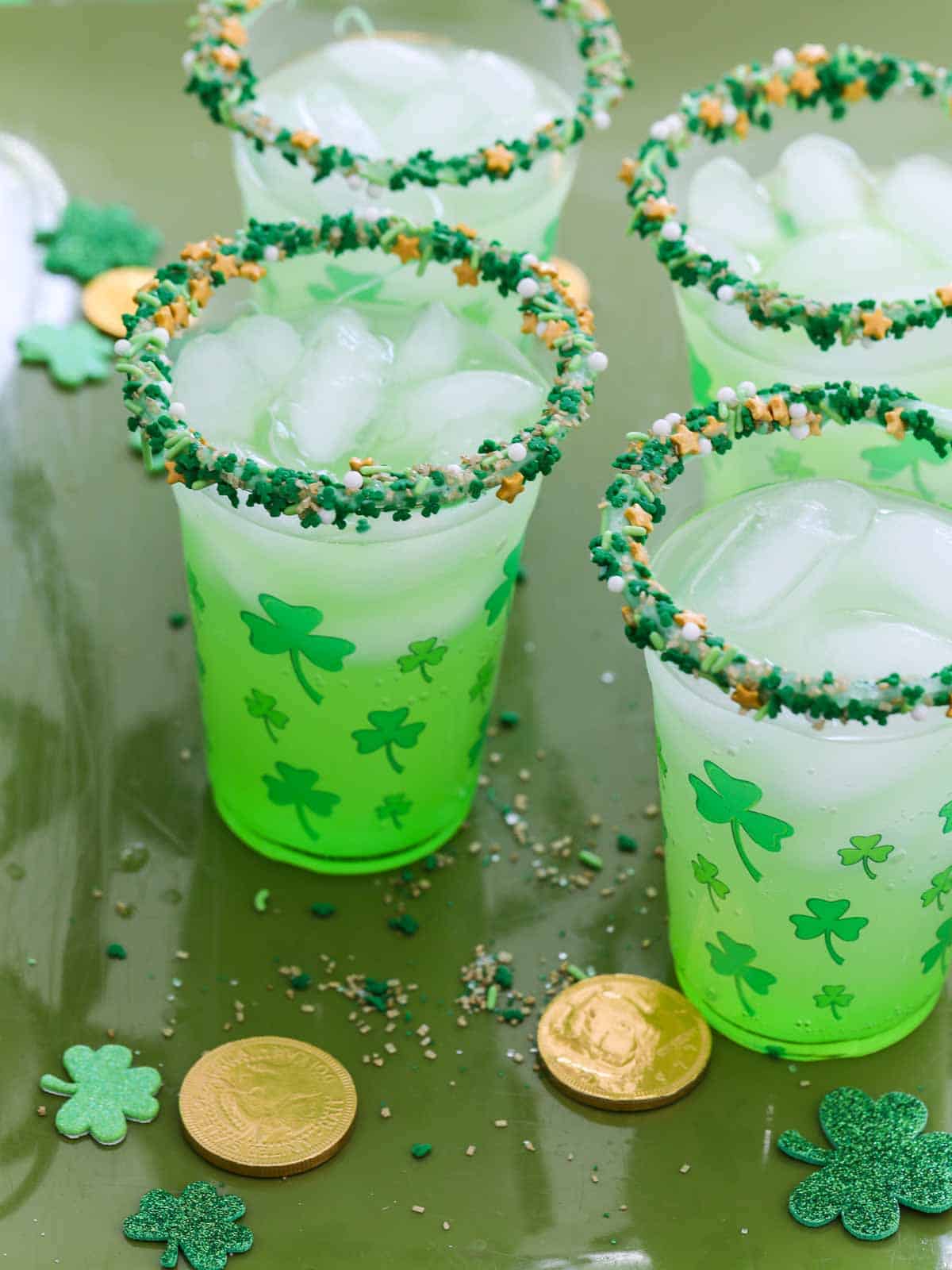 Four green cocktails on a tray with gold coins for St. Patrick's day.