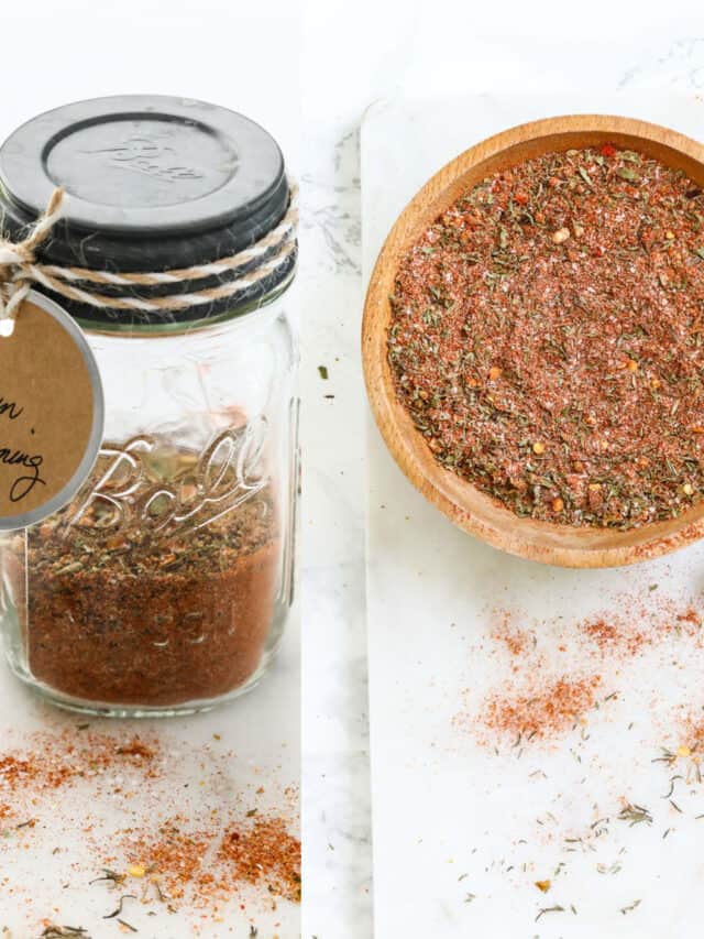 A small glass mason jar filled with Cajun seasoning with a label and it in a wooden bowl.