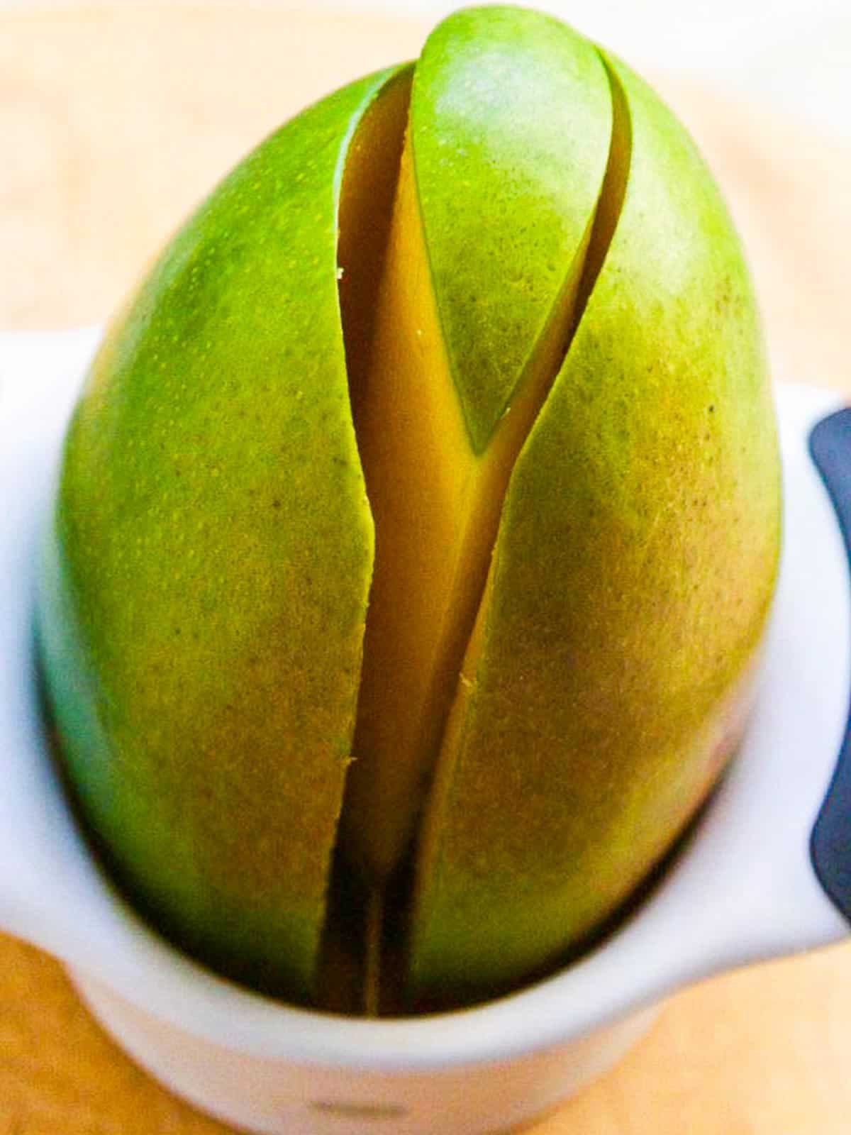 A mango splitter tool showing how to cut a mango in half removing the seed.