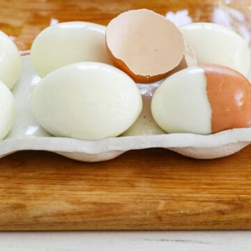 6 perfectly hard boiled eggs with a cracked half of an egg shelf on top.