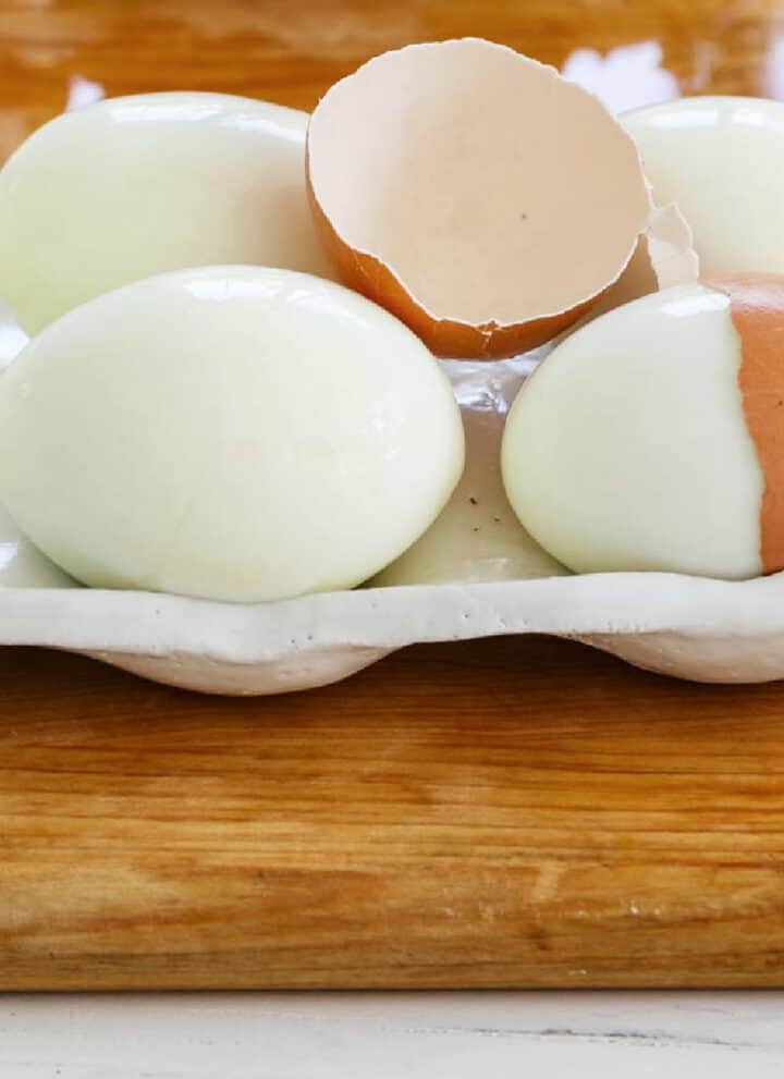 6 perfectly hard boiled eggs with a cracked half of an egg shelf on top.