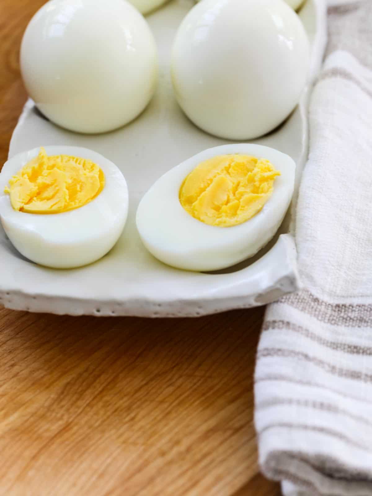 A white ceramic dish with a hard boiled egg sliced open on the dish.