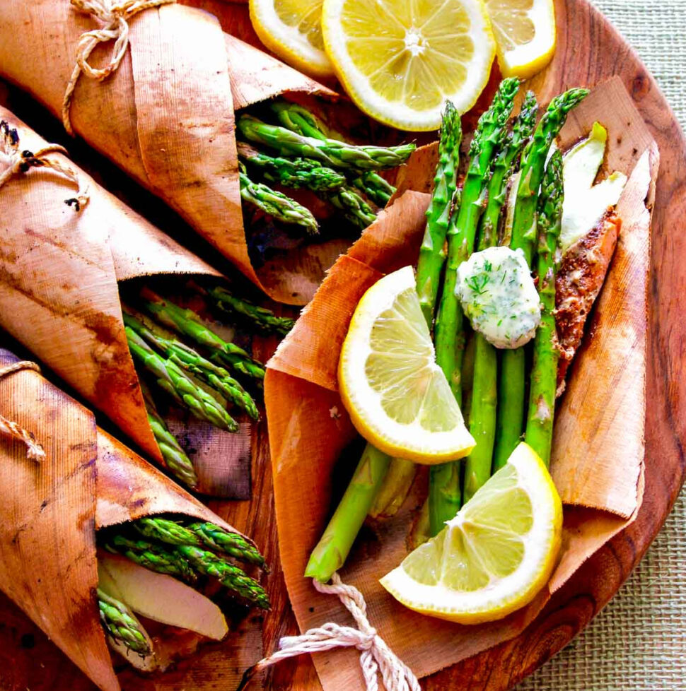 A wooden platter with cedar wrapped salmon, asparagus, and lemon butter.