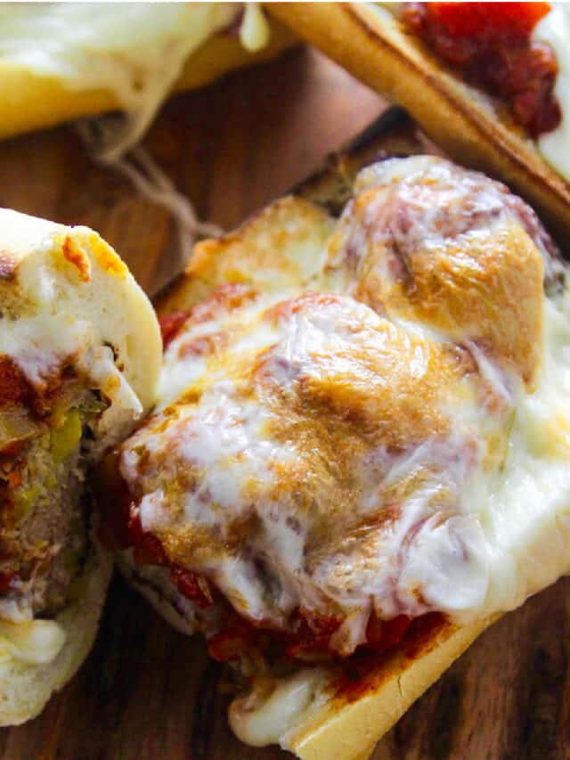 A meatball sub with marinara sauce and melted golden gooey cheese on a toasted baguette.