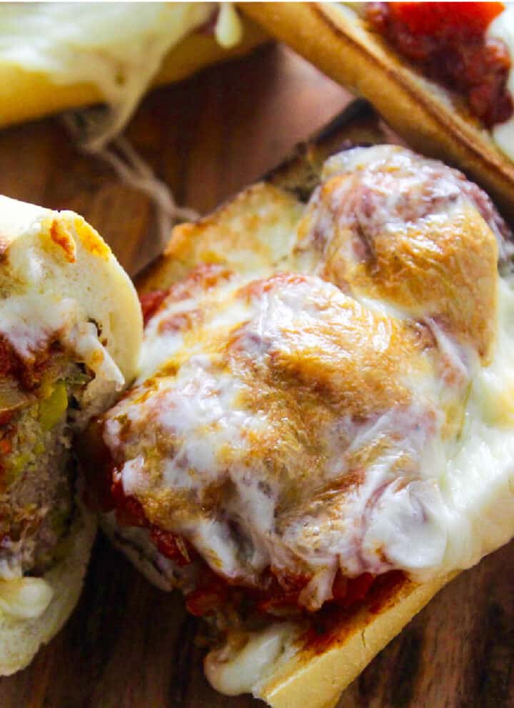 A meatball sub with marinara sauce and melted golden gooey cheese on a toasted baguette.