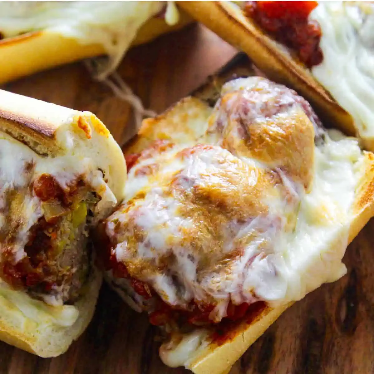 A meatball sub with marinara sauce and melted golden gooey cheese on a toasted baguette.