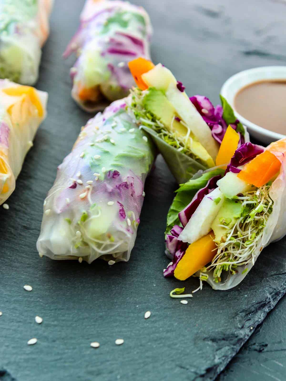 A close up of a A sliced open spring roll made with rice paper wrapper stuffed with colorful veggies.