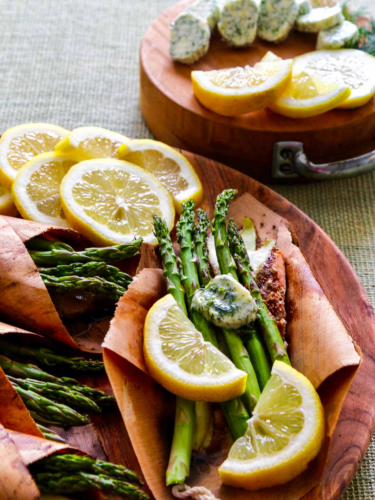 Melting herb lemon butter on asparagus with cedar salmon and garnished with lemon slices.