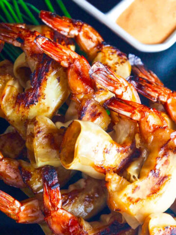 A firecracker shrimp recipe with two dipping sauces on a black platter.